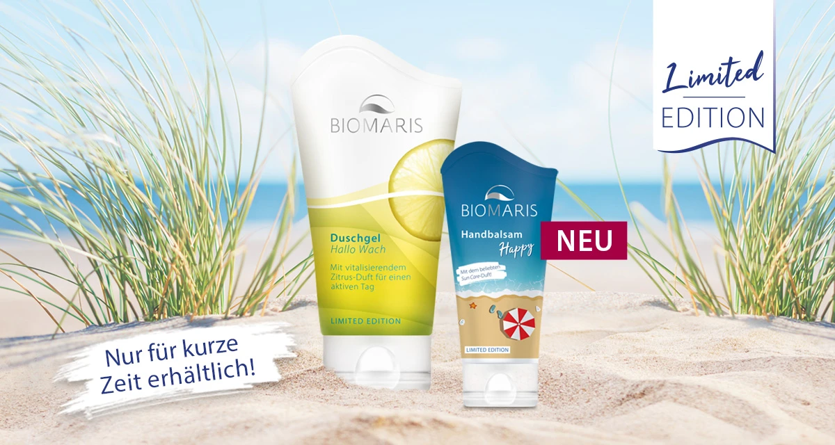 Limited Editions Duschgel Hallo Wach und Handbalsam Happy in Tuben mit Klappdeckel im Sand vor Strandkulisse mit Dünen und Meer