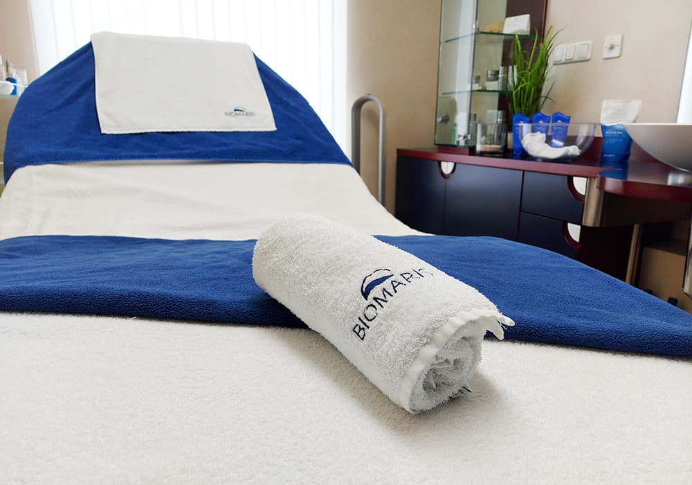 BIOMARIS Kosmetik-Institut Kabine BIOMARIS Kosmetik-Institut Liege mit blau-weißer Auflage und gerolltem Handtuch