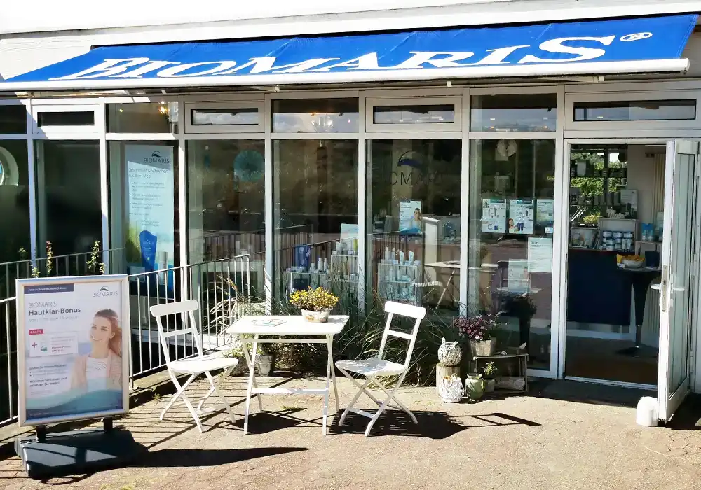 Shop Baltrum Eingang des BIOMARIS-Shops auf Baltrum mit Werbeschild und Sitzgruppe vor der Glasfassade