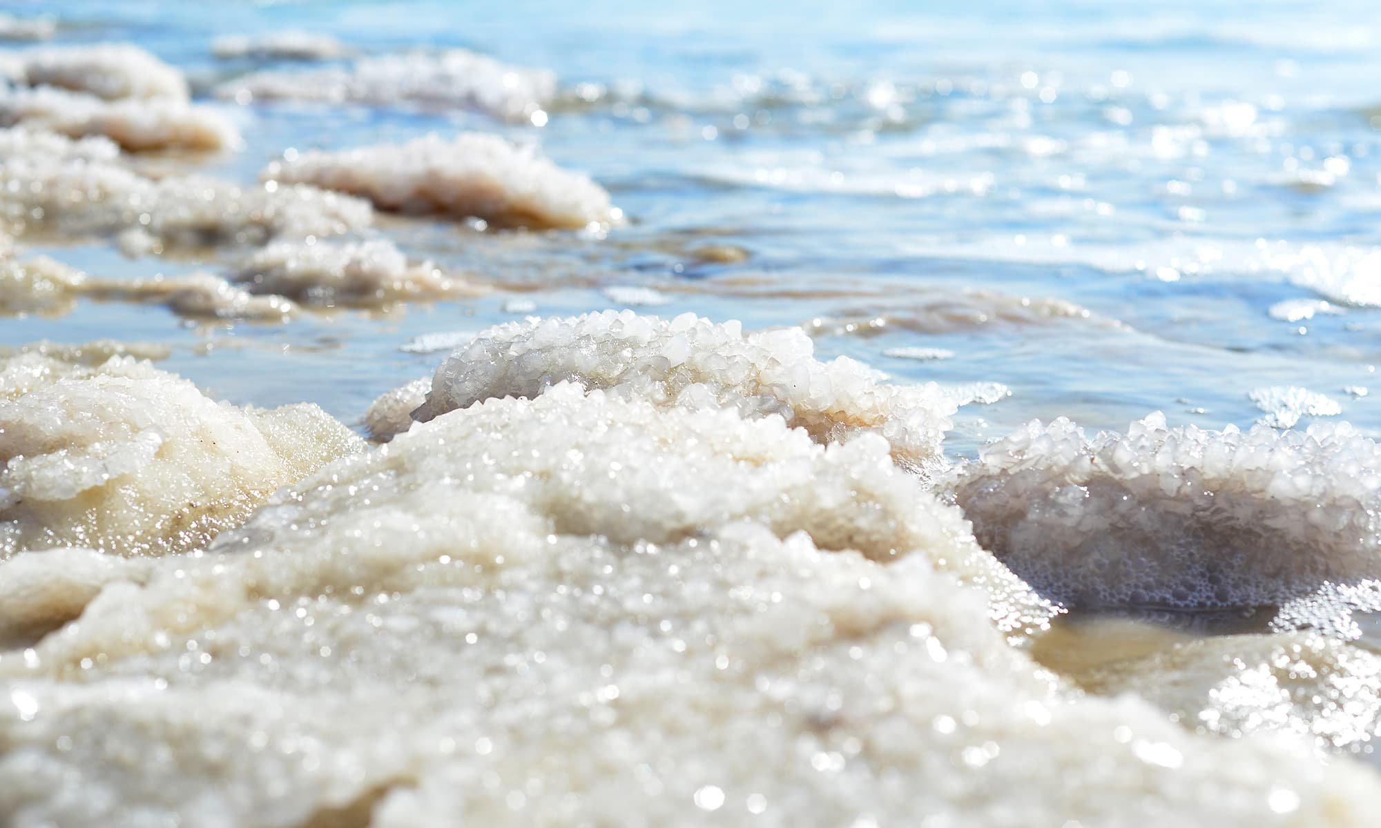 Meersalz Salzablagerungen an einem Meeresufer mit glitzernden Kristallen und blauem Wasser
