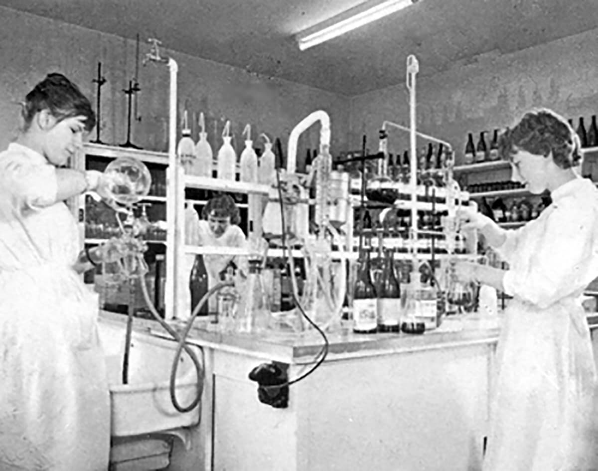 Laborarbeit 1971 Drei Frauen in weißen Kitteln arbeiten konzentriert in einem Labor mit Glasgeräten und Reagenzflaschen.