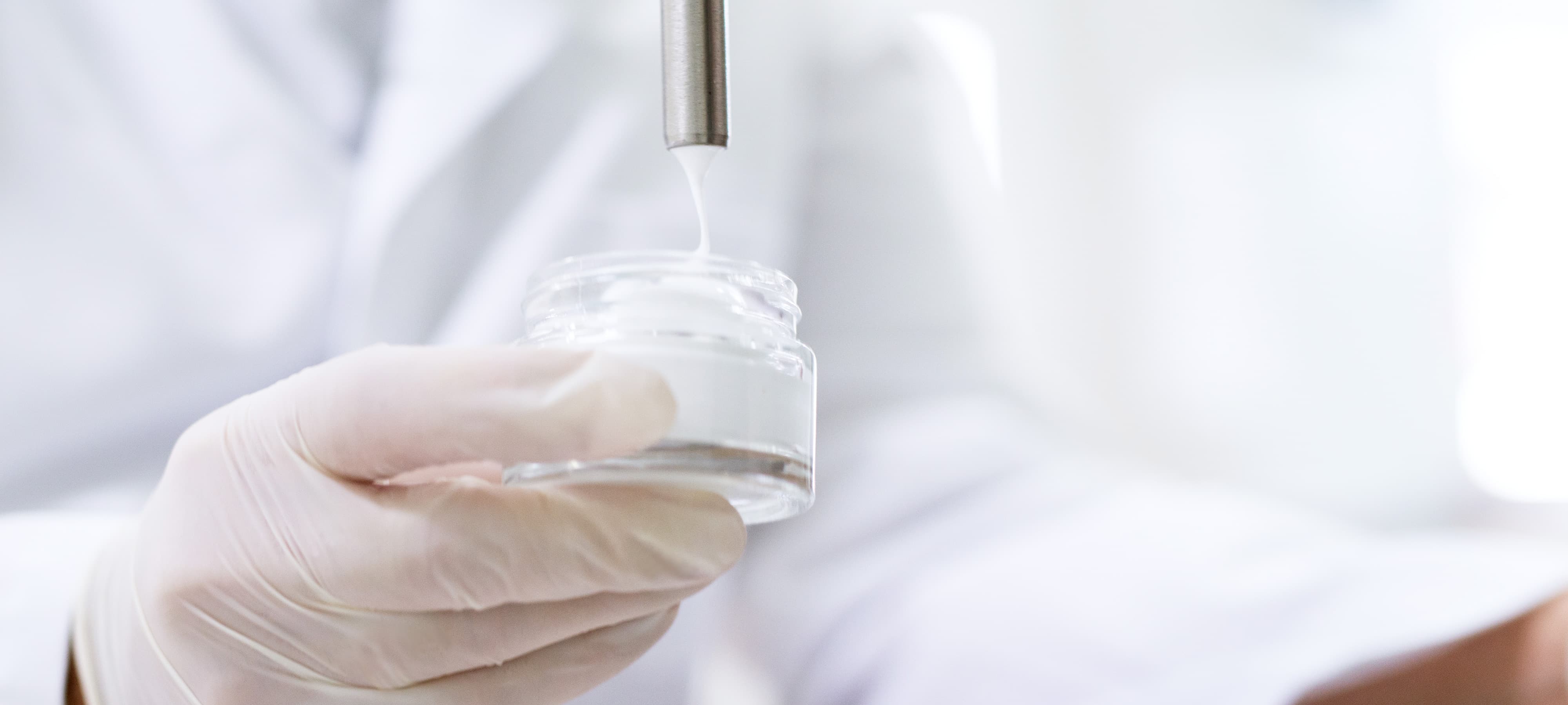 Laborarbeit Nahaufnahme: Labormitarbeiter füllt weiße Creme in Glastiegel ab