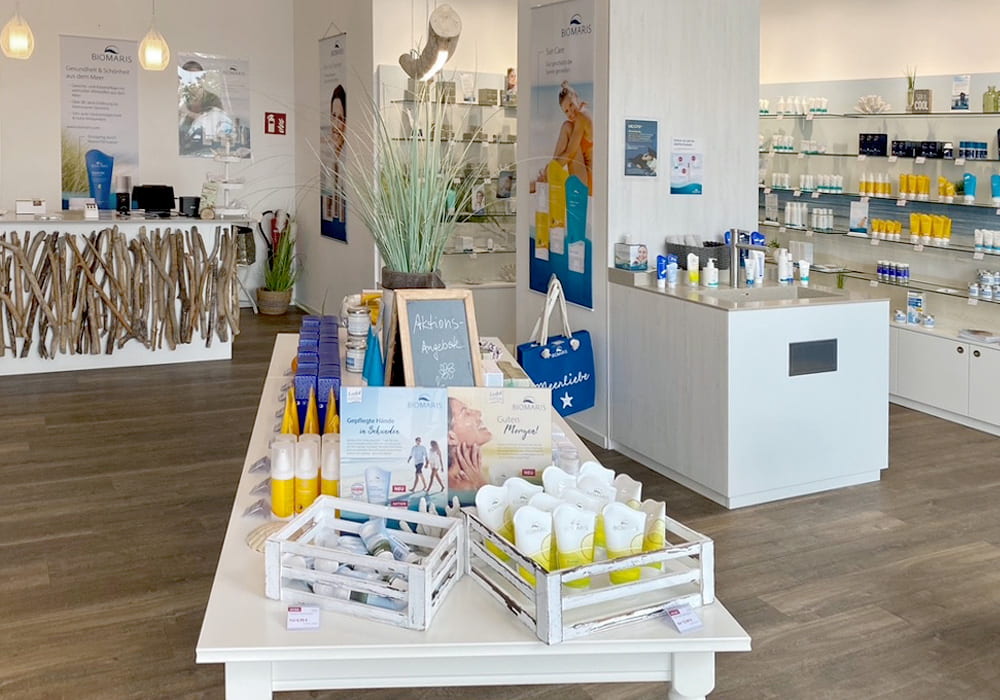Innenraum des BIOMARIS Shops mit Aktionsprodukten auf zentralem Tisch und Theke, im Hintergrund Verkaufsregale mit Produkten